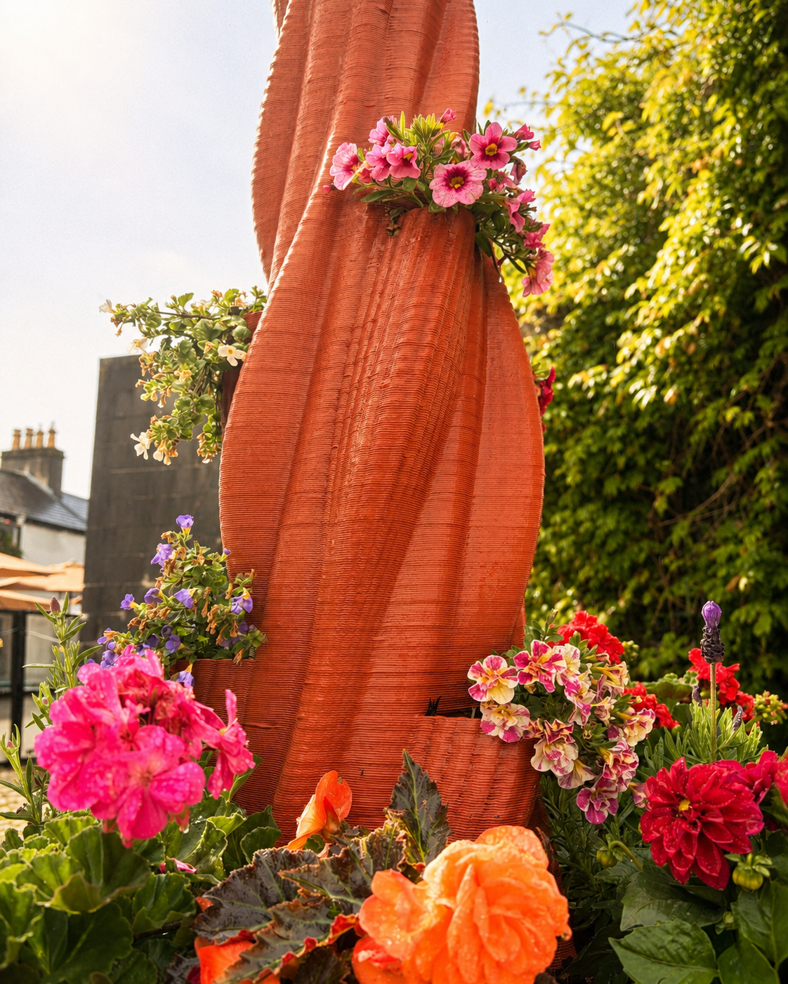 Tall terracotta 3D-printed Kildare installation with flowering plants in integrated pockets