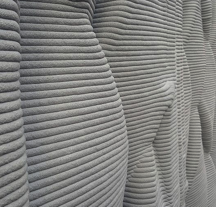 Close-up of a 3D-printed concrete surface showing layered horizontal ridges