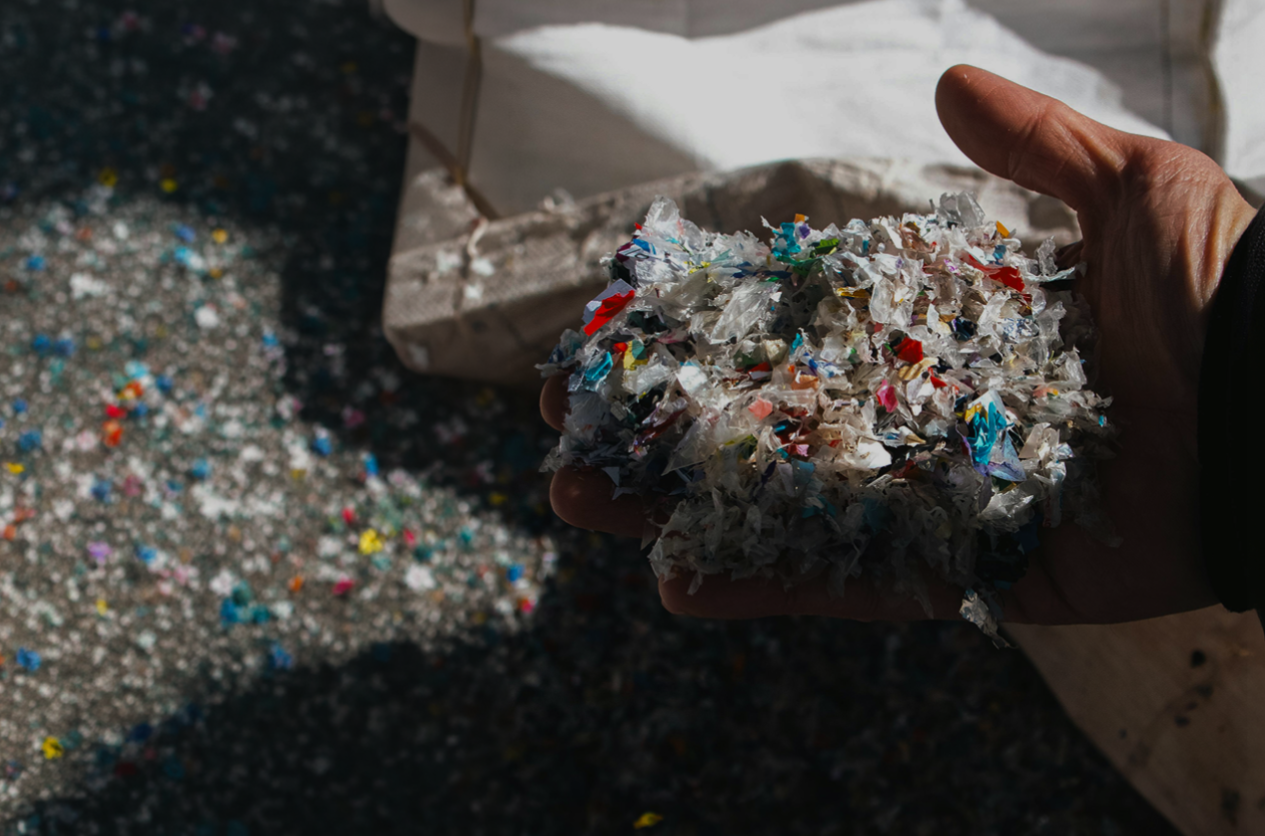 Hand holding shredded recycled plastic flake from the closed-loop material system