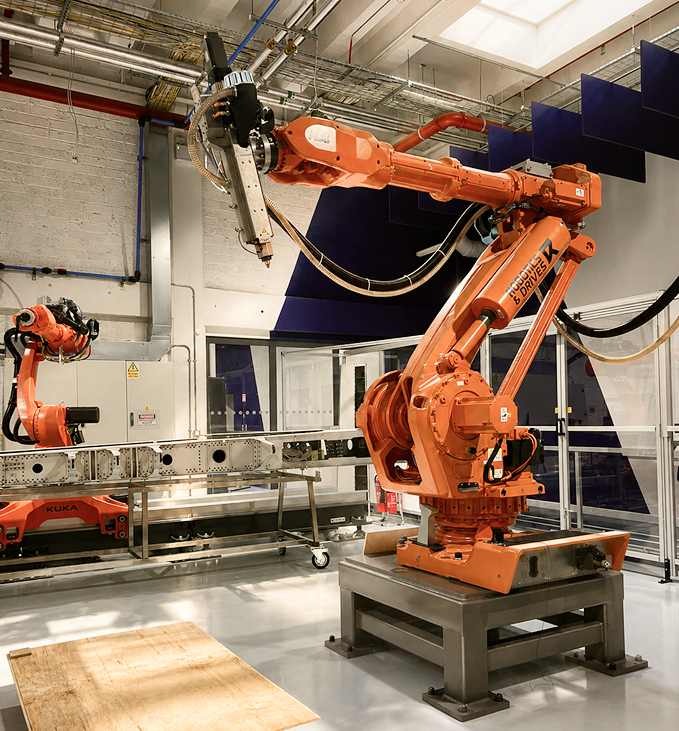 KUKA robotic arm printing on a plywood bed in the Zerolab workshop