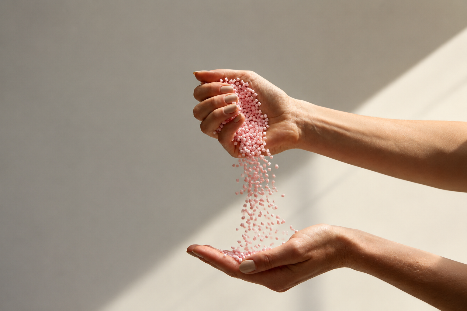 Hands pouring recycled polymer pellets, the raw feedstock for closed loop large format 3D printing